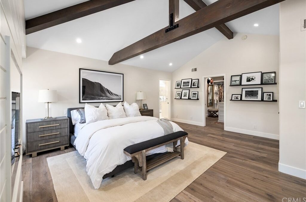A spacious masterbedroom featuring hardwood flooring and a brown/cream color scheme.