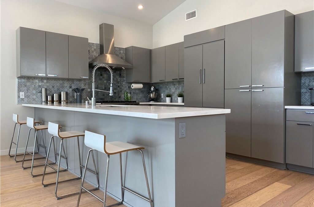 Updated kitchen interior with wood flooring and a marble countertop.