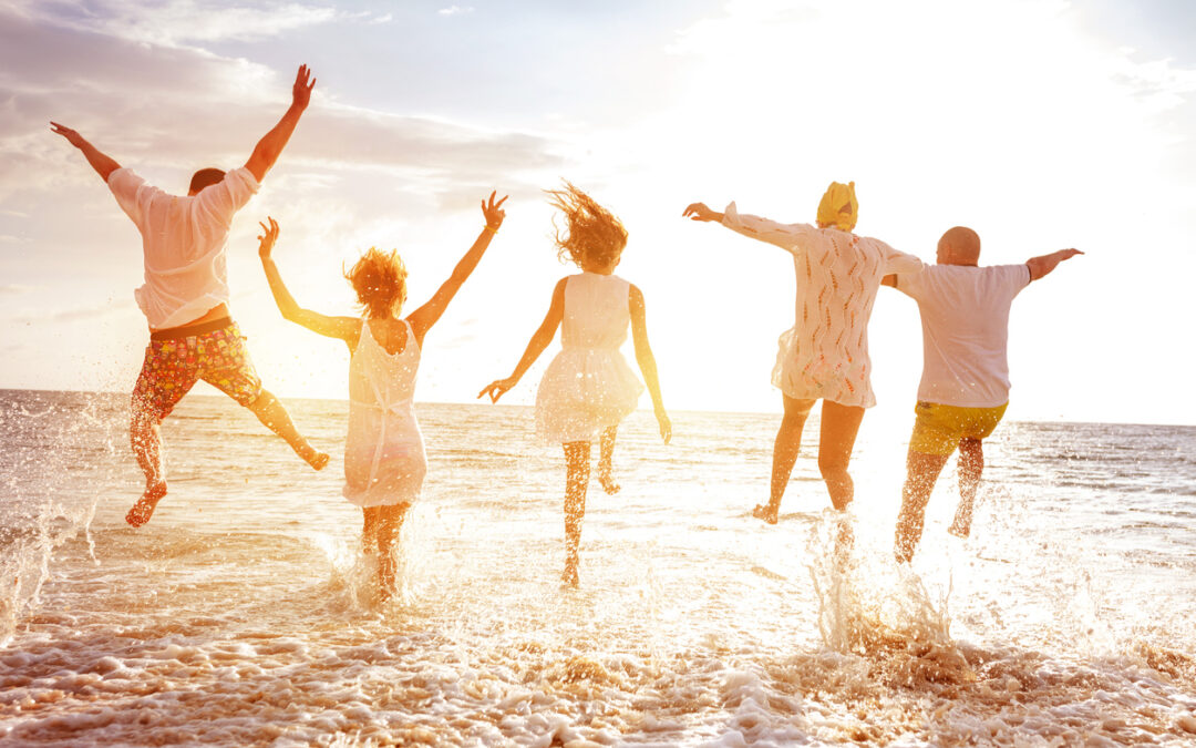 Group of five happy peoples run and jump to sea beach against sunset sun